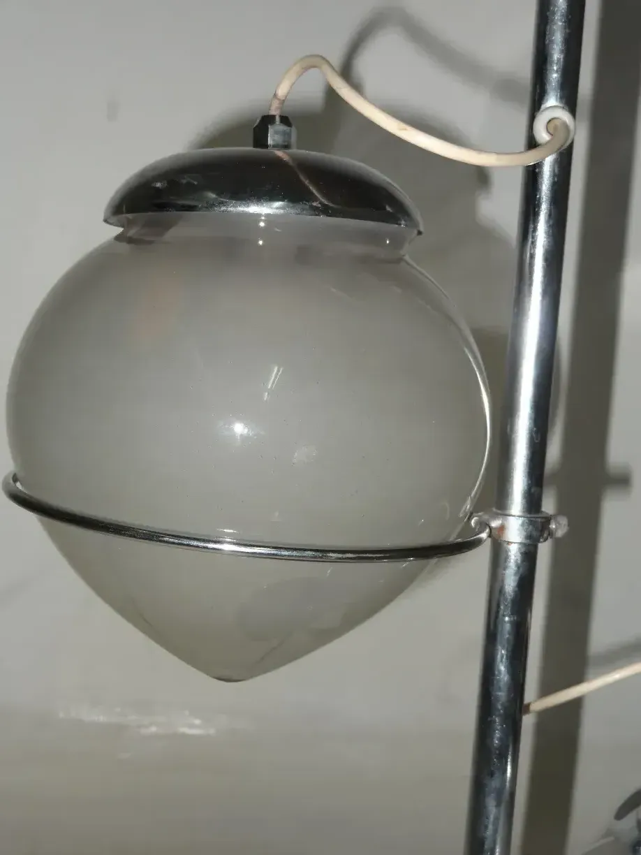 Luminária de mesa antiga com formato esférico e detalhes metálicos, ambiente minimalista.