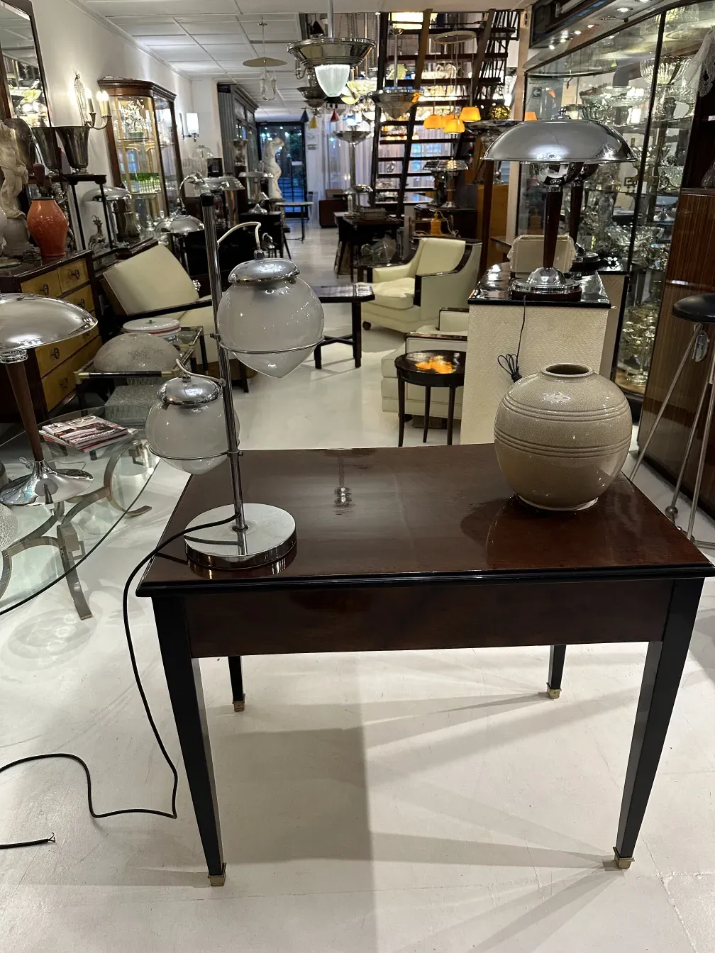 Luminária de mesa antiga com base brilhante e detalhes claros em um ambiente elegante.