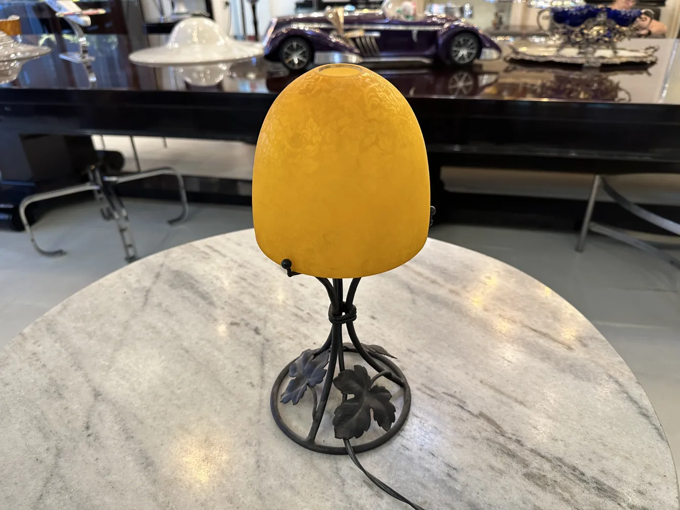 Visão de uma luminária de mesa antiga com abajur amarelo sobre uma mesa de mármore