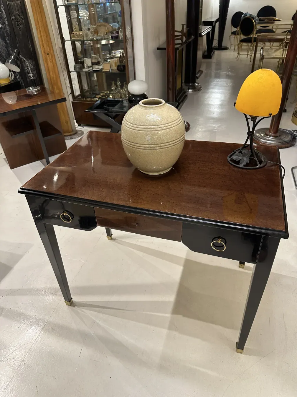 Luminária de mesa antiga com base decorativa e luz amarela, em um ambiente de antiguidades.