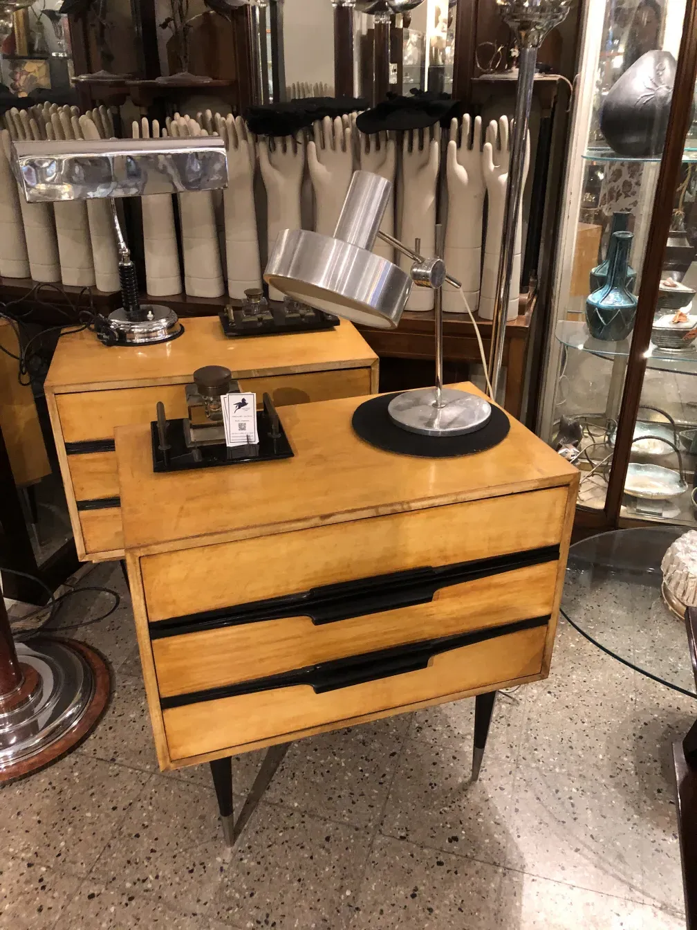 Luminária de mesa antiga com formato elegante e cor prateada, cercada por outros objetos