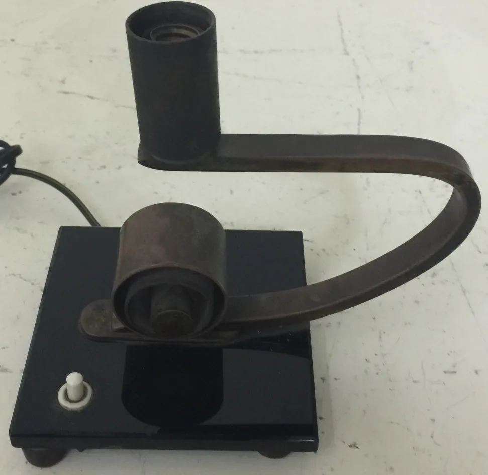 Luminária de mesa antiga com design moderno e base preta, em um ambiente neutro.