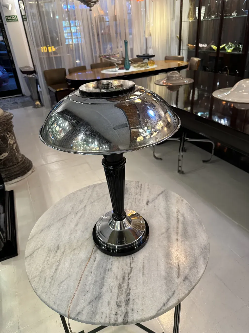 Luminária de mesa antiga com superfície brilhante e design elegante, em um ambiente aconchegante