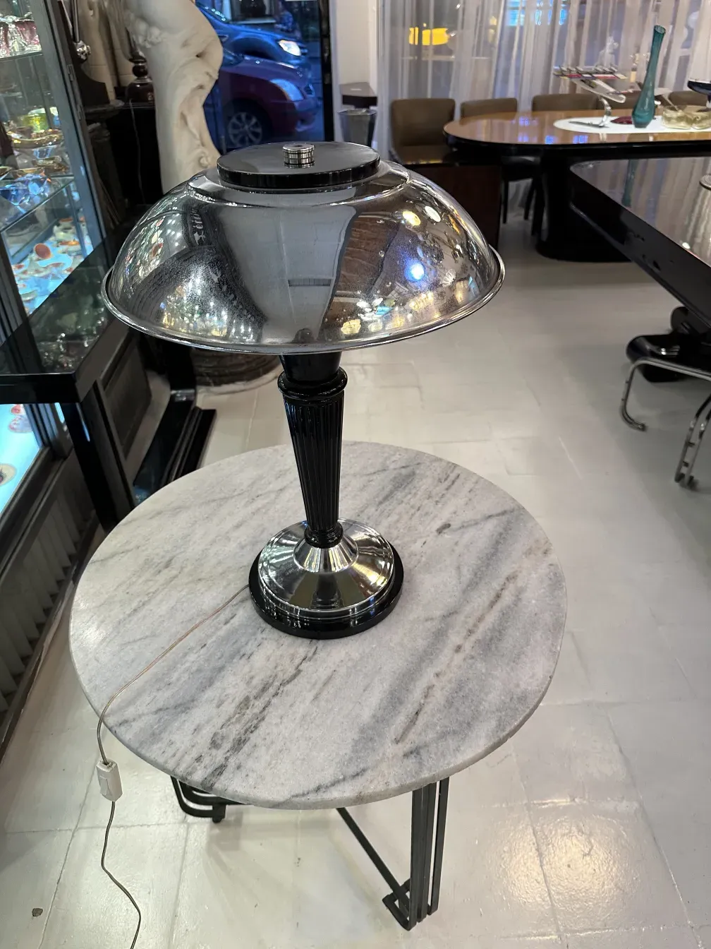 Luminária de mesa antiga com base brilhante e cúpula redonda em um ambiente elegante.