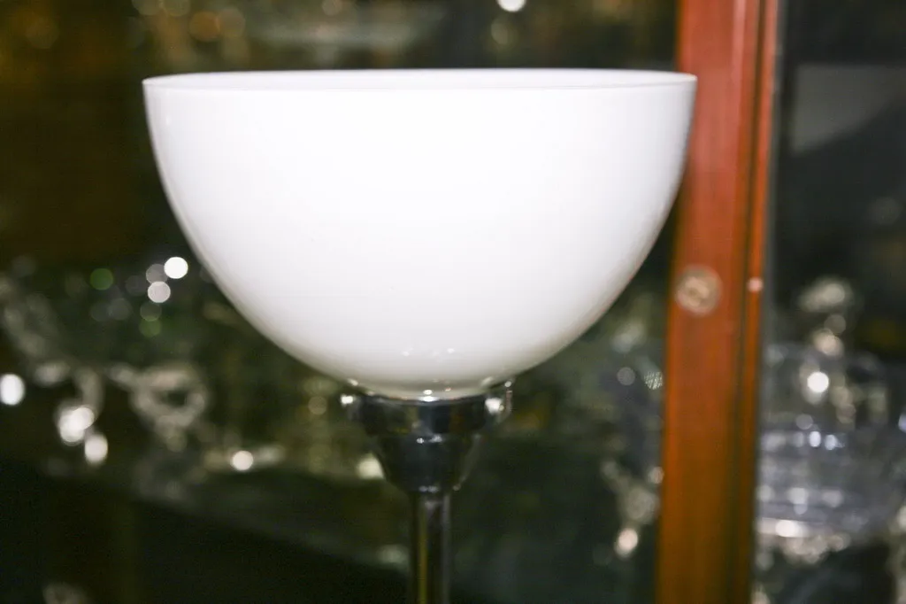 Luminária de mesa antiga branca com base elegante em um ambiente de antiguidades.