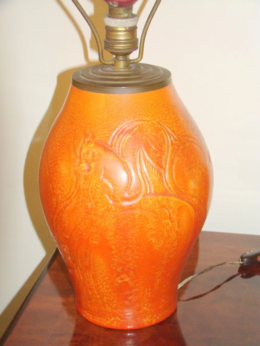 Luminária de mesa antiga com acabamento laranja, design mitológico, ambiente acolhedor.