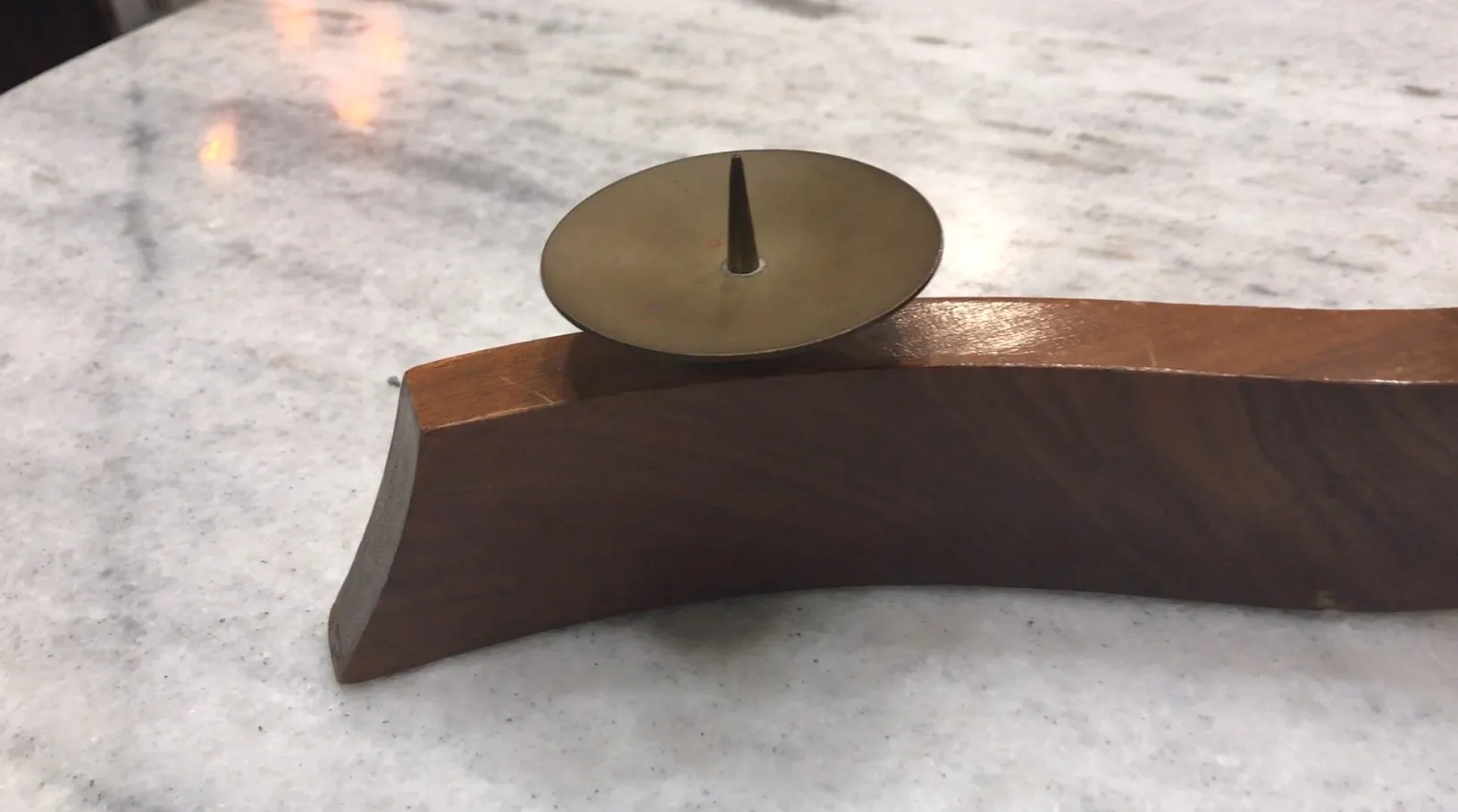 Antique candelabra with a curved base and simple center detail on a marble table.