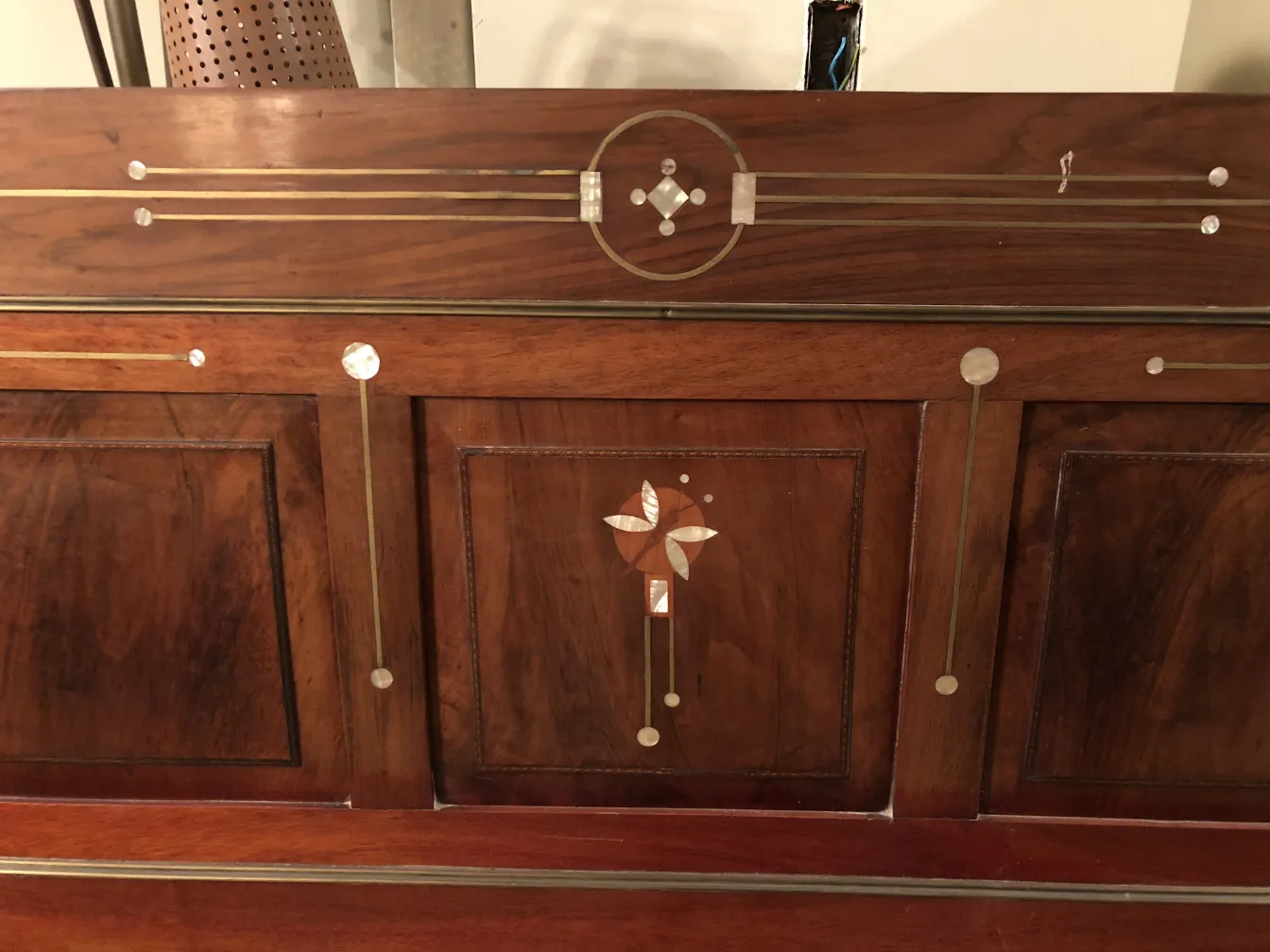 headboard of an antique bed with decorative wood design, shiny details