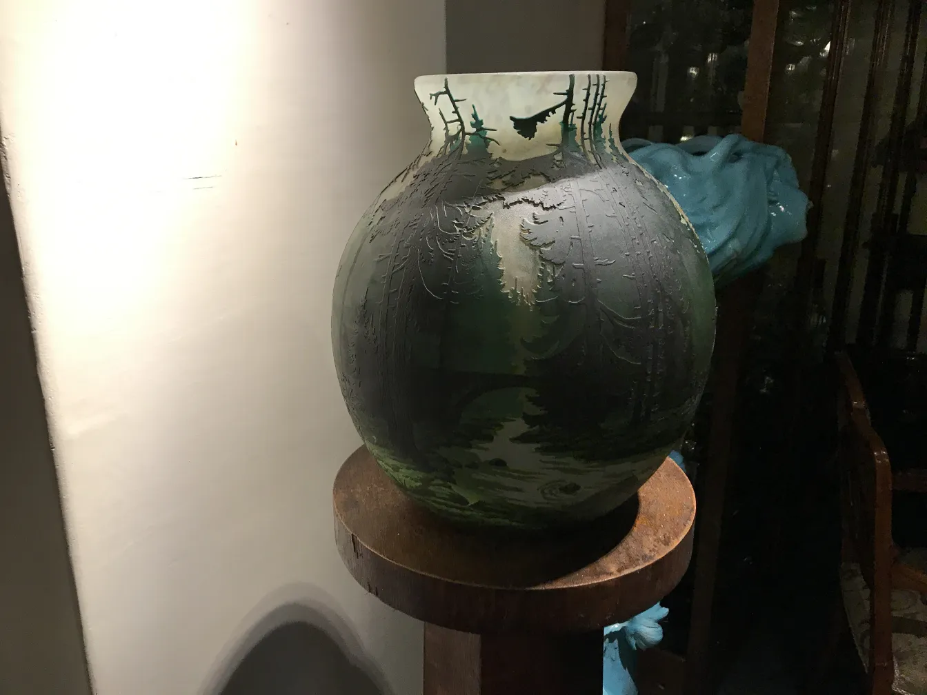 Vidro assinado de Muller Fres com decoração inspirada na natureza em tons escuros, exibido em uma prateleira de madeira.