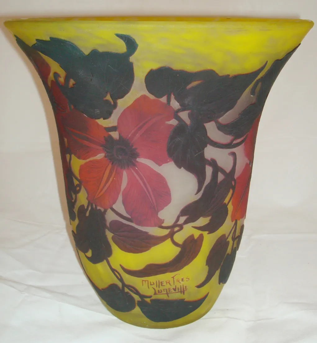 Elegante vaso antigo assinado por Muller Freres, decorado com flores vermelhas e verdes sobre um fundo amarelo, com assinatura visível.