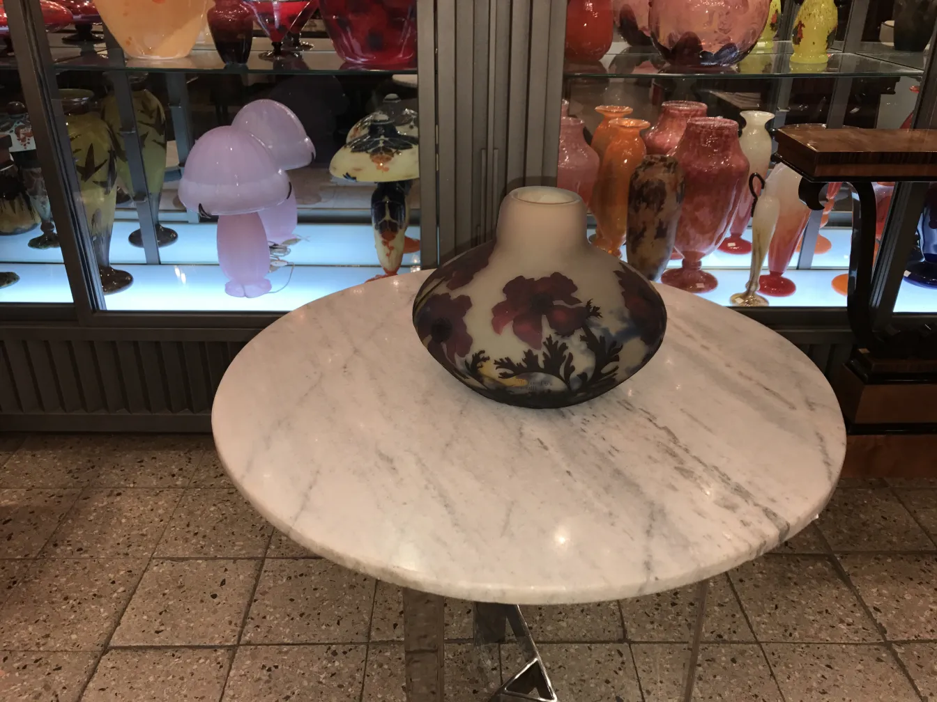 Vidro assinado de muller fres com desenho floral sobre uma mesa de mármore.