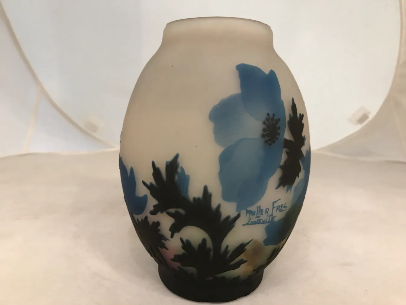 Vidro assinado por Muller Fres com desenho floral azul sobre fundo claro.