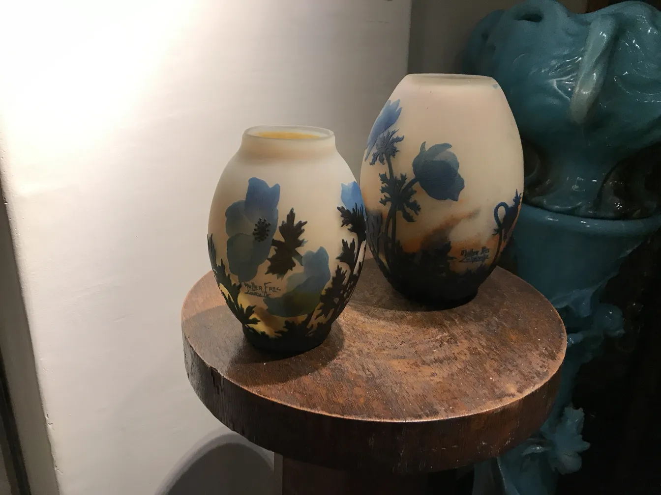 Dois vasos antigos de vidro assinado Muller Fres sobre uma mesa de madeira.