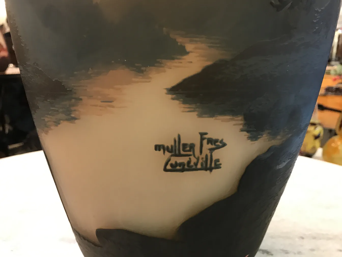 Vidro antigo assinado por Muller Fres, com assinatura visível e design artístico, em um ambiente de antiguidades.