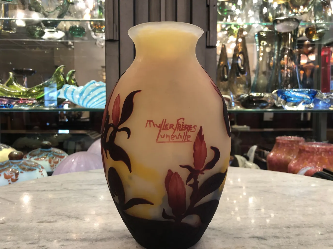 Vaso com design floral de vidro assinado Muller Fres em ambiente de antiguidades