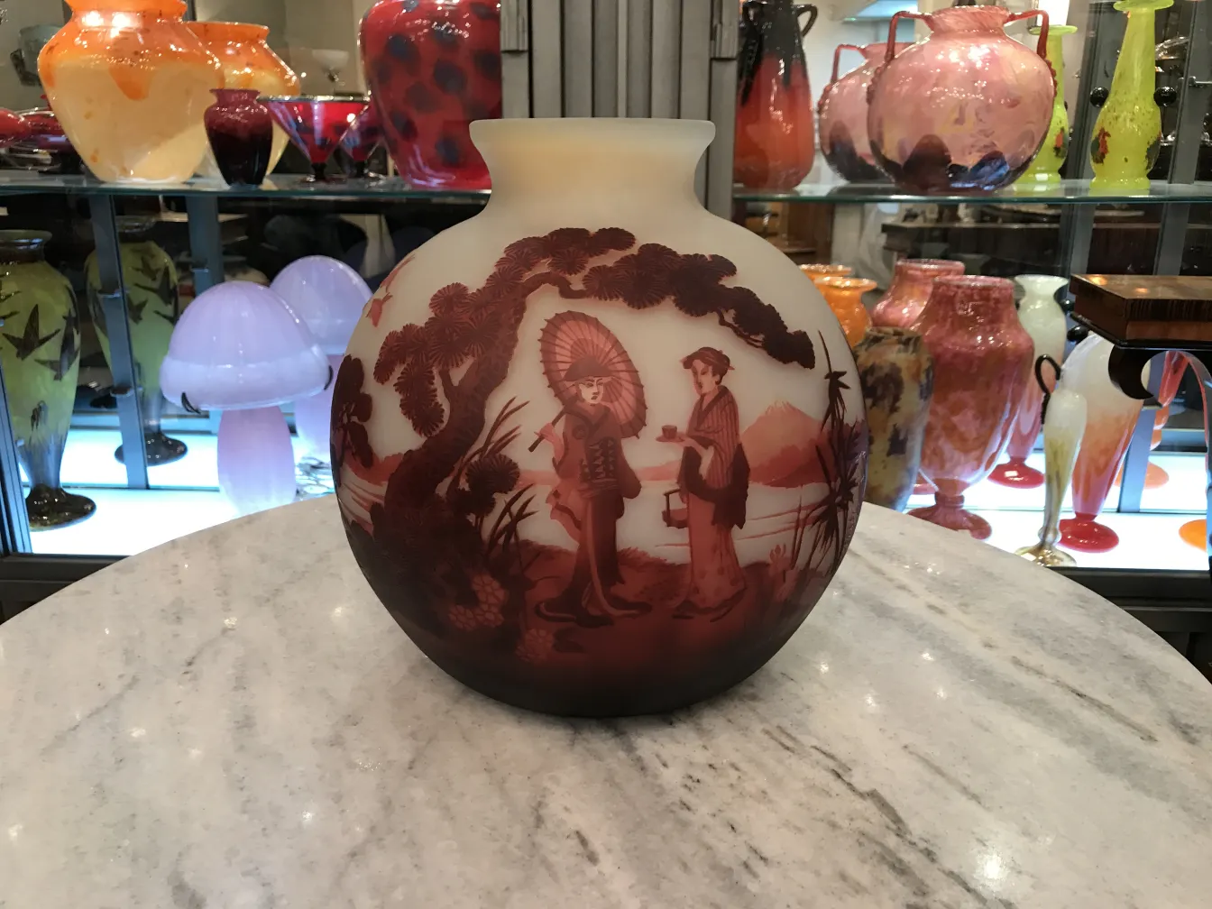 Belo vaso com figuras em tons vermelhos, antiguidade muller fres rodeado por outros itens decorativos.