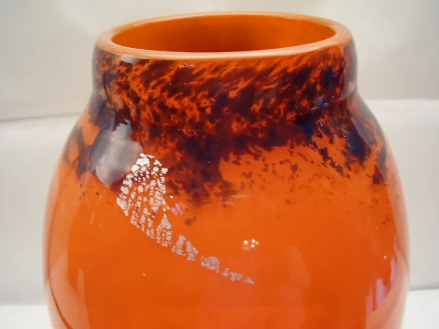 Vidro tubular assinado laranja com padrões escuros.