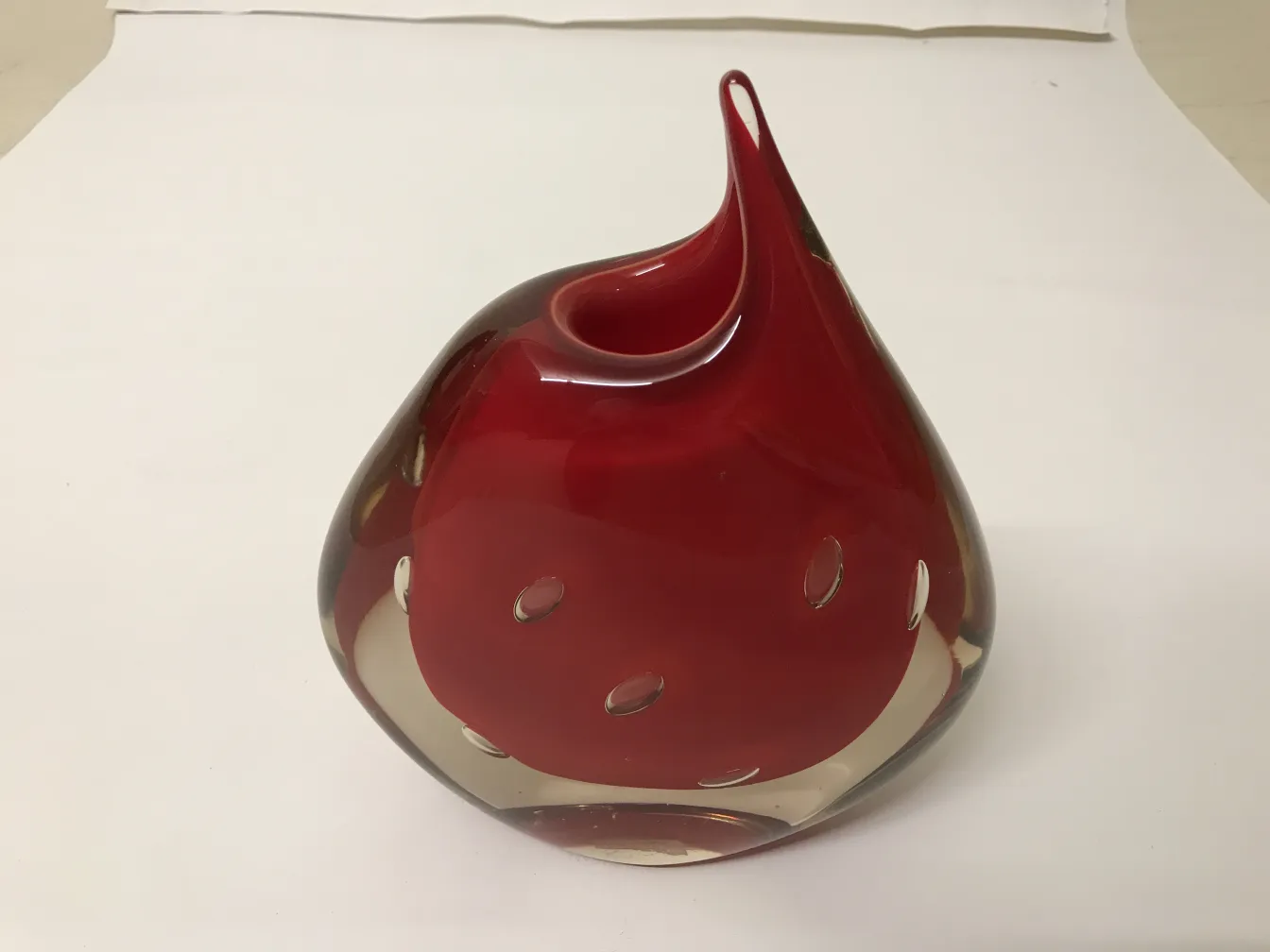 antique murano vase with curvy design in red and gold on white background