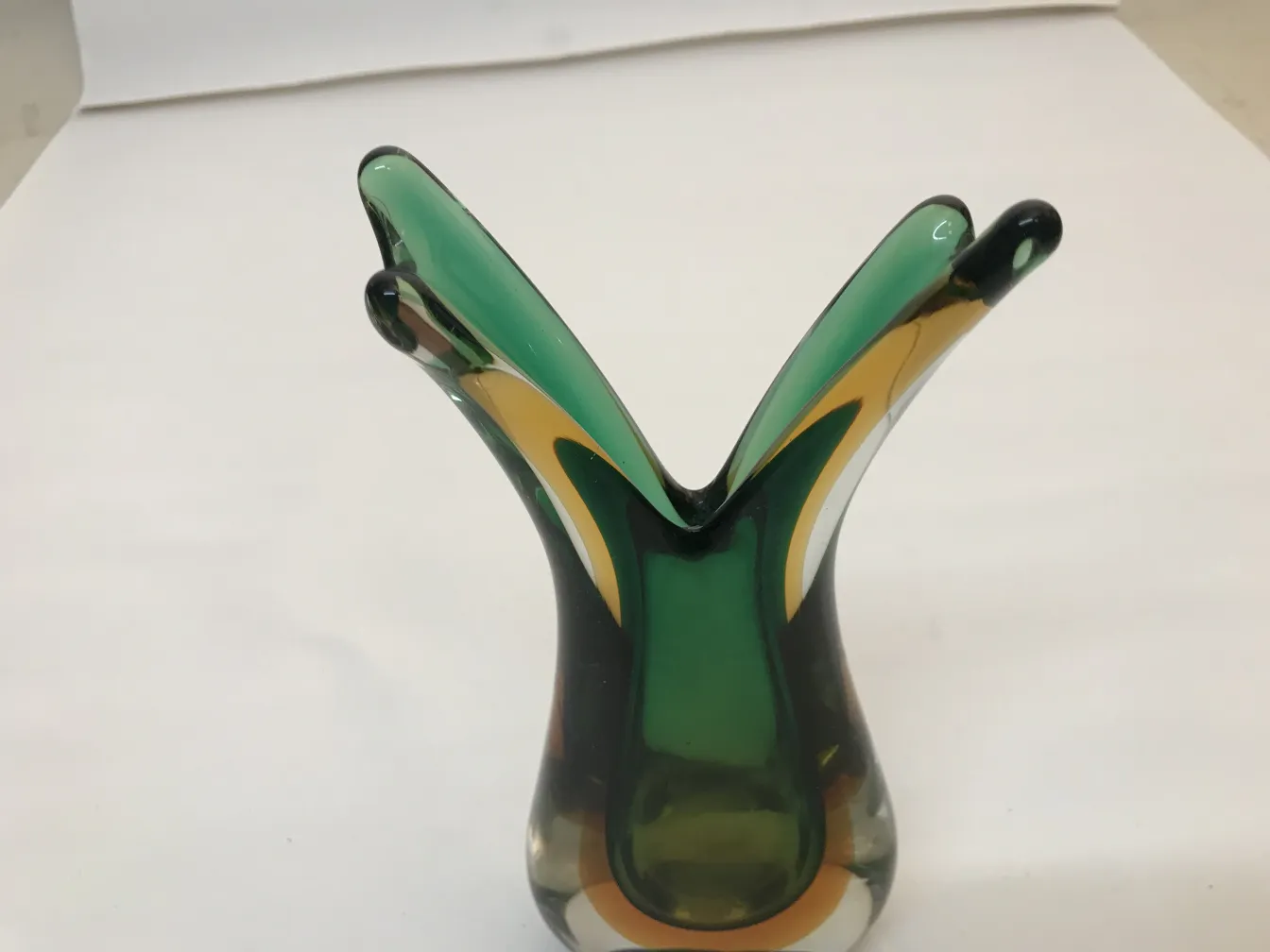 murano vase with a stylized shape and vibrant colors, set against a neutral background.