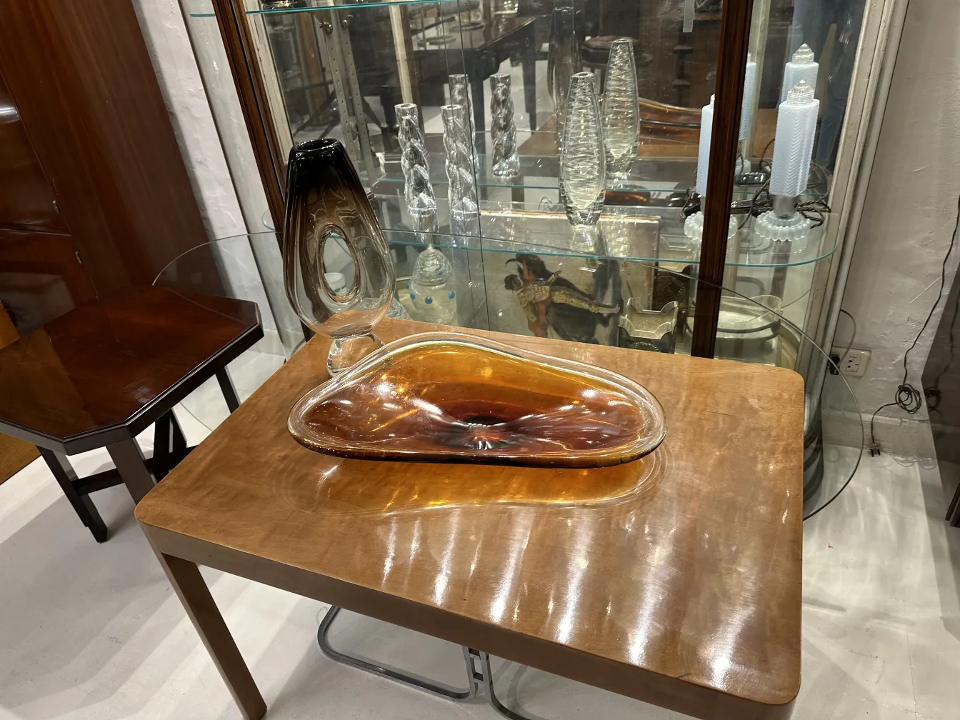 Antique Murano vase with unique shape in amber and black tones, on a wooden table.