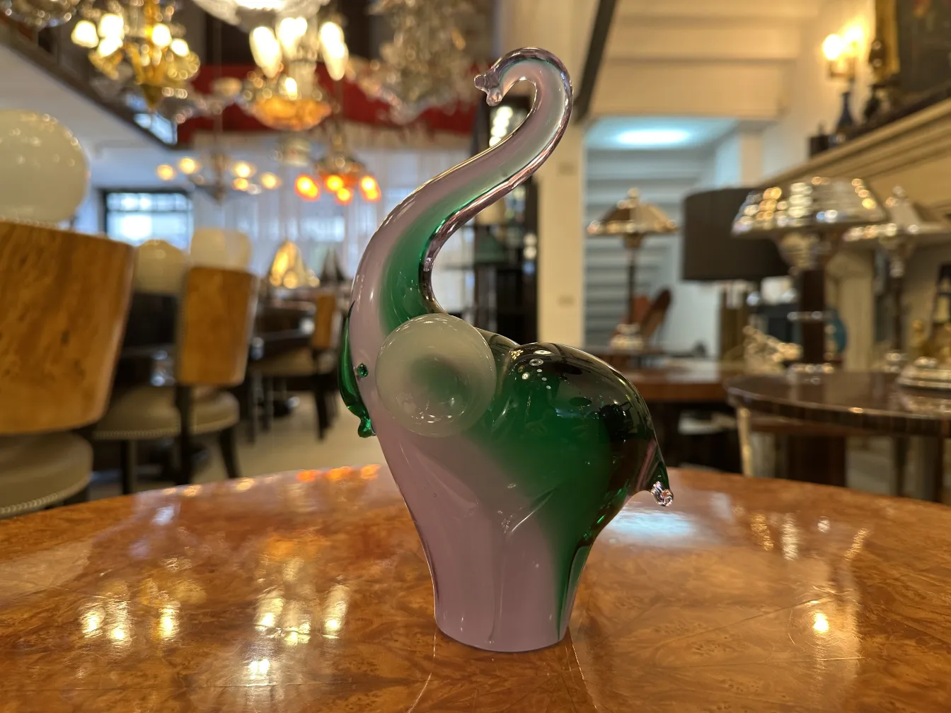 glass elephant with green and purple details on antique furniture background