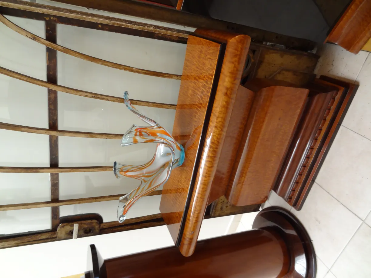 Murano glass with orange and blue design on an antique wooden table.