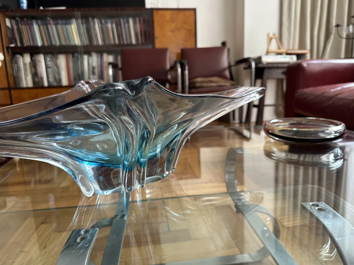 Antique Murano glass in blue with fluid shapes on a glass table.