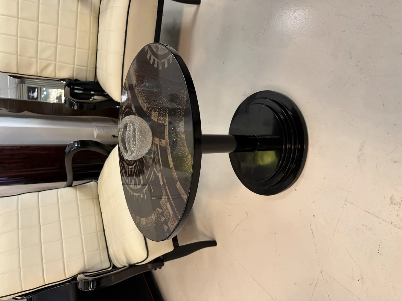 round murano glass on black table, surrounded by light chairs