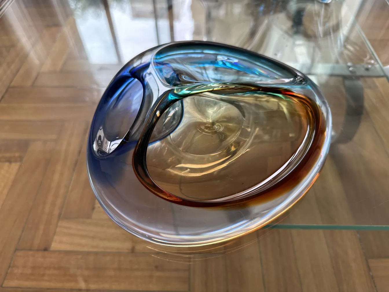 Beautiful murano glass with blue and amber tones, on a wooden table.