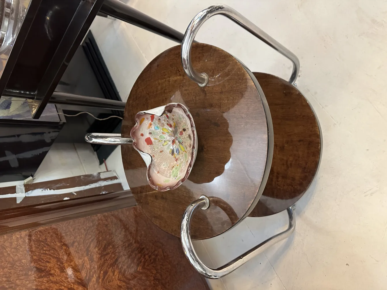 Antique Murano glass in vibrant colors shaped like a flower on a wooden table.