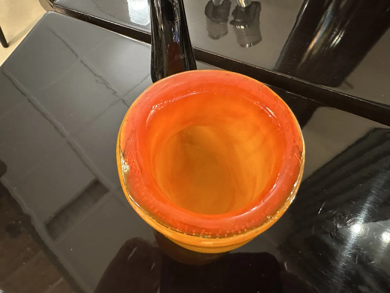 Antique Murano glass in orange color with a smooth and shiny shape, set in a modern ambiance.