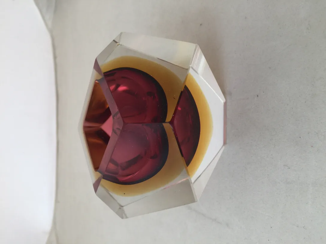 Antique Murano glass with round design and vibrant colors, set against a neutral background.