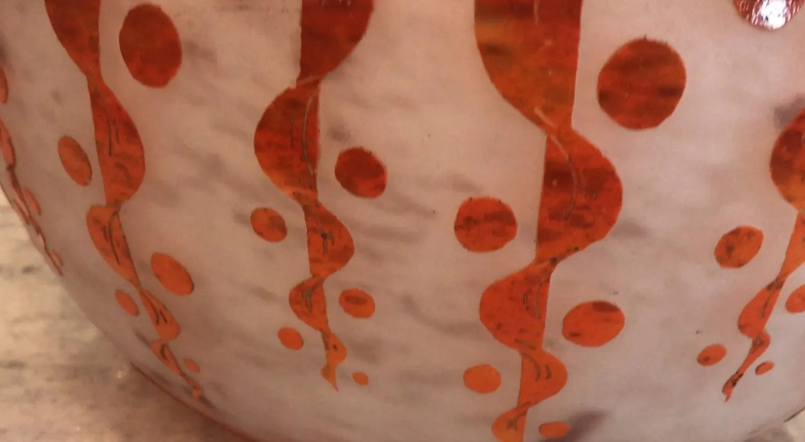 Antique signed glass with orange details and rounded shape.