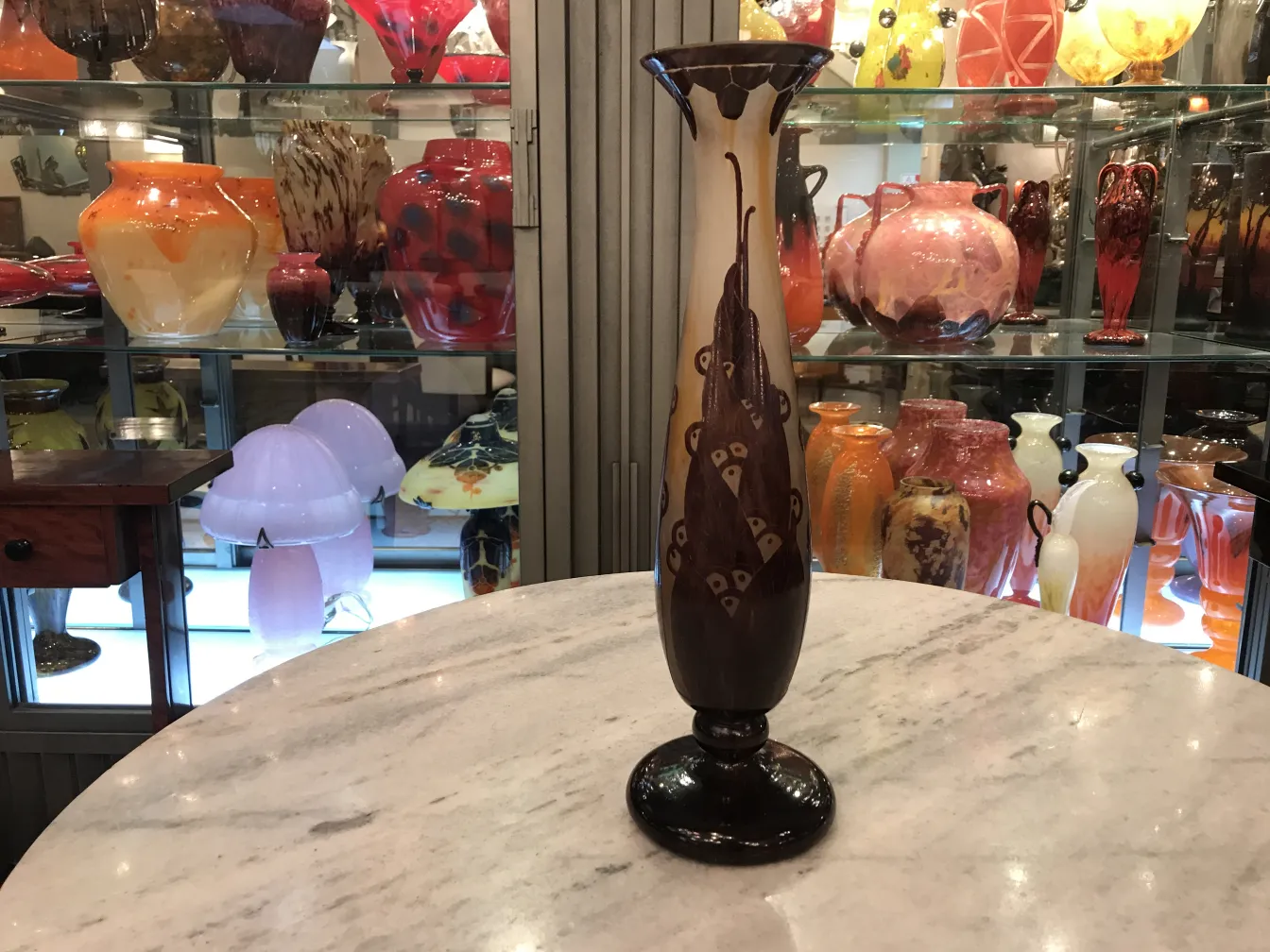 Vase with ornate design, light background, on a shelf with other decorative items