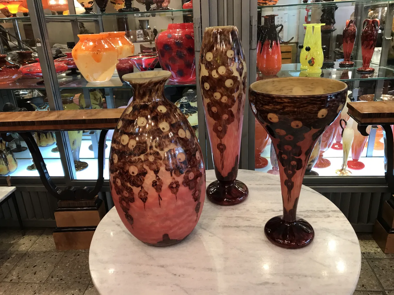 Vases and glassware with antique design and vibrant colors in a display case.