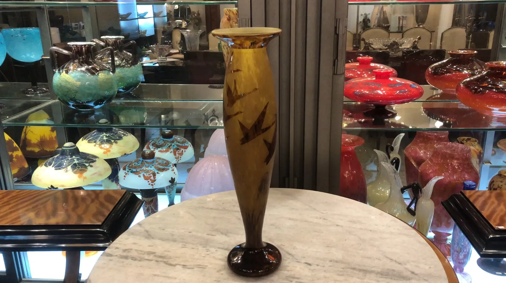 Decorative glass vase signed Le Verre on display among antiques.