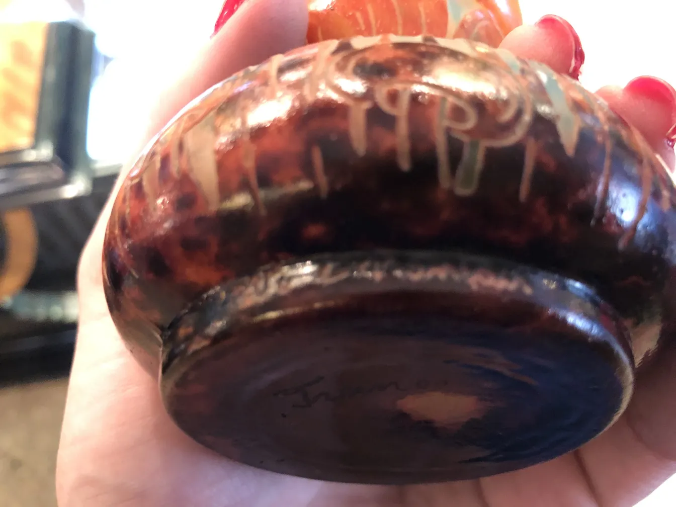 Antique glass base with visible signature, blurred background.