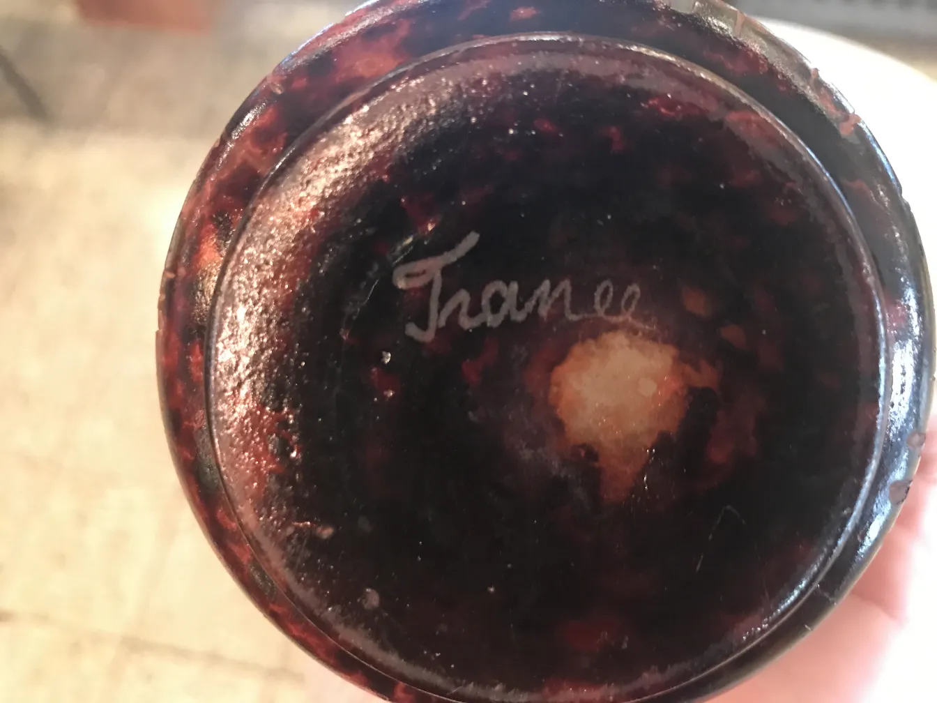 View of the base of a signed le verre glass in dark tones with a visible signature.