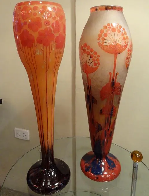 Two signed glass vases with floral decoration in warm tones.
