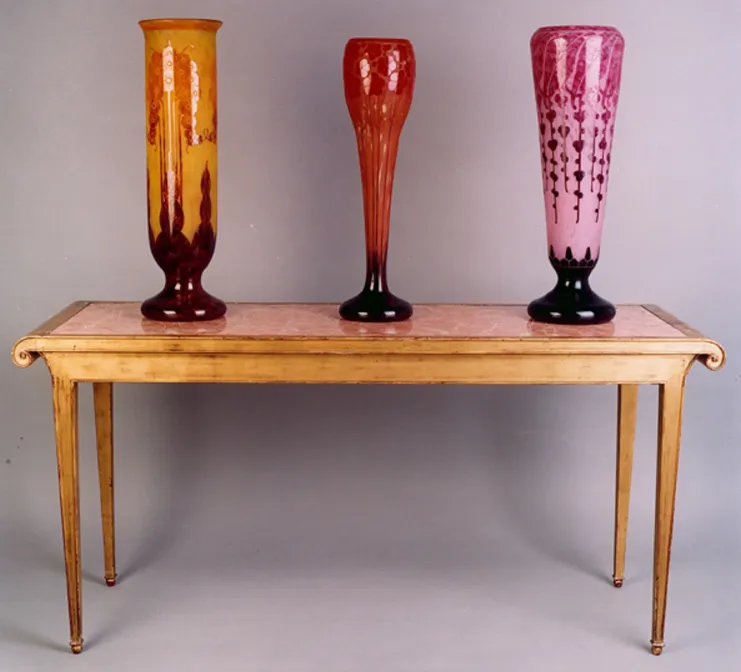 Three antique glass vases, varying colors and shapes, neutral background.
