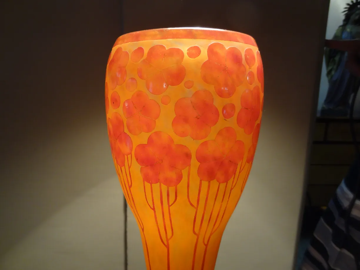 Antique signed glass Le Verre with orange floral design on light background.