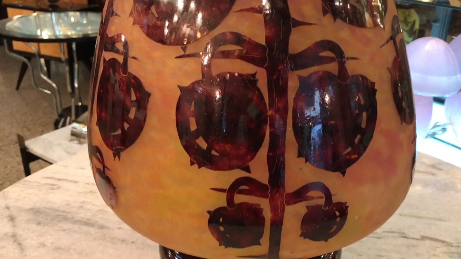 Antique glass vase with warm tones, featuring decorative drawings.