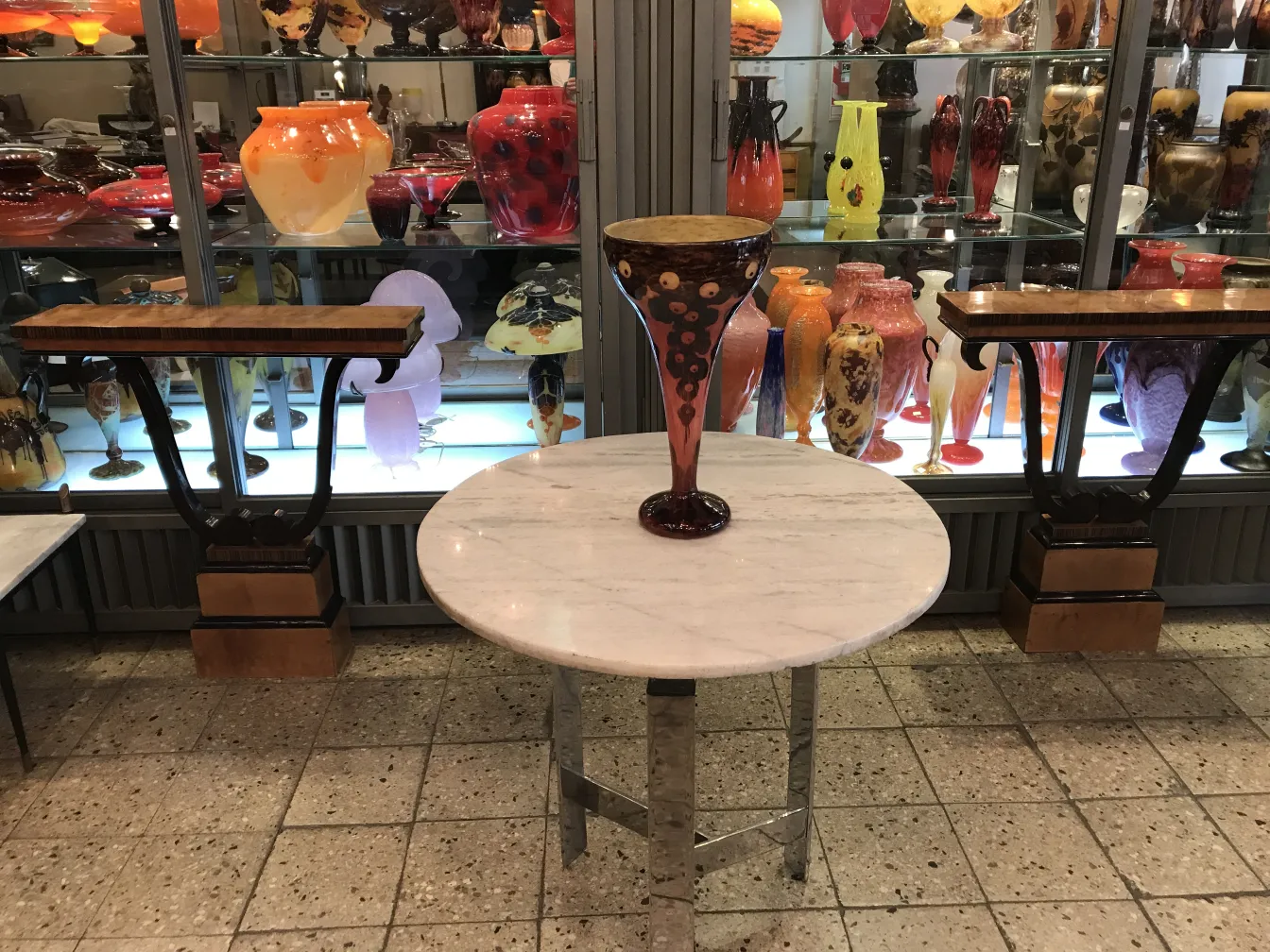 Colorful signed glass vase on display with shelves