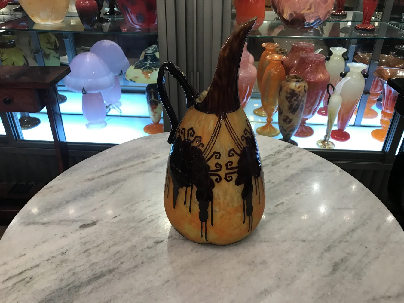 Antique glass piece with decorative design and signature in front, light background