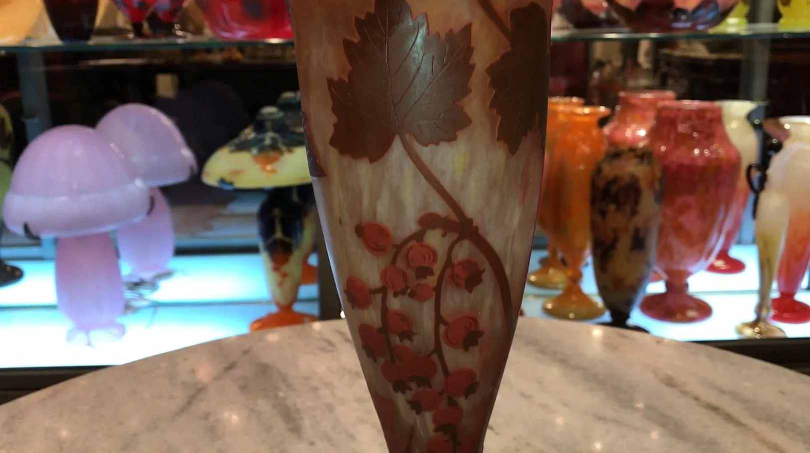 signed glass Daum Nancy with leaf and flower design on light background, surrounded by other antique items