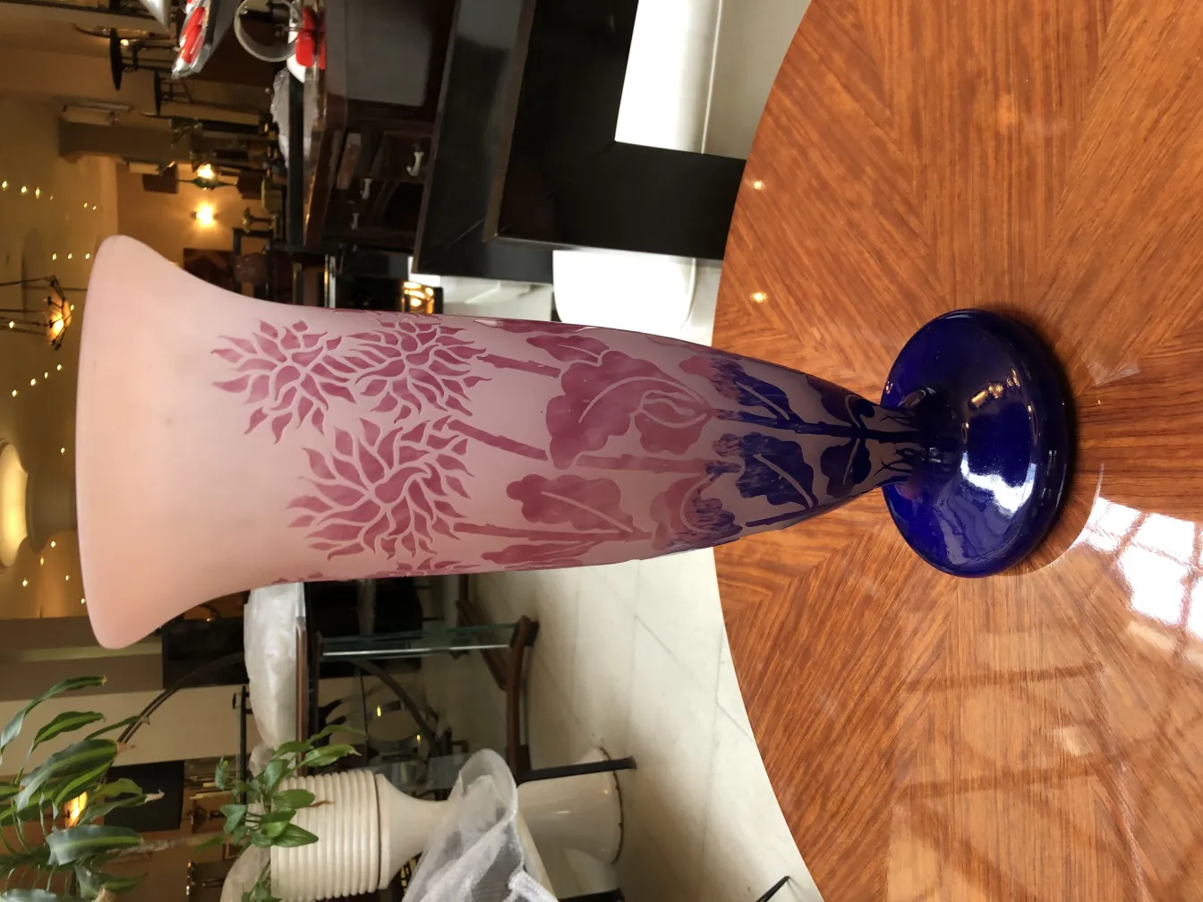 Vaso de vidro assinado degué com padrão floral e base azul, em ambiente de antiguidades.