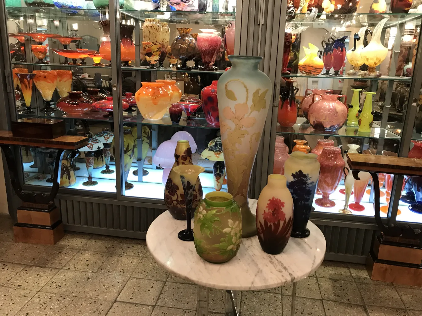 signed Gallé glass on display with colorful decorative jars