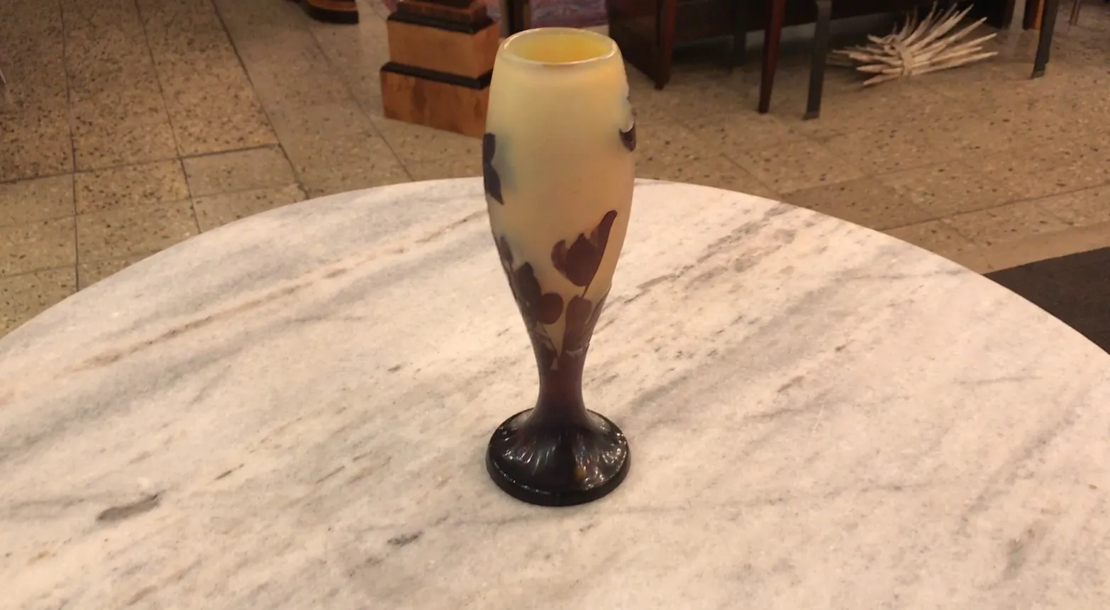 antique signed glass Gallé, decorated with dark flowers on a light background, in an antique environment