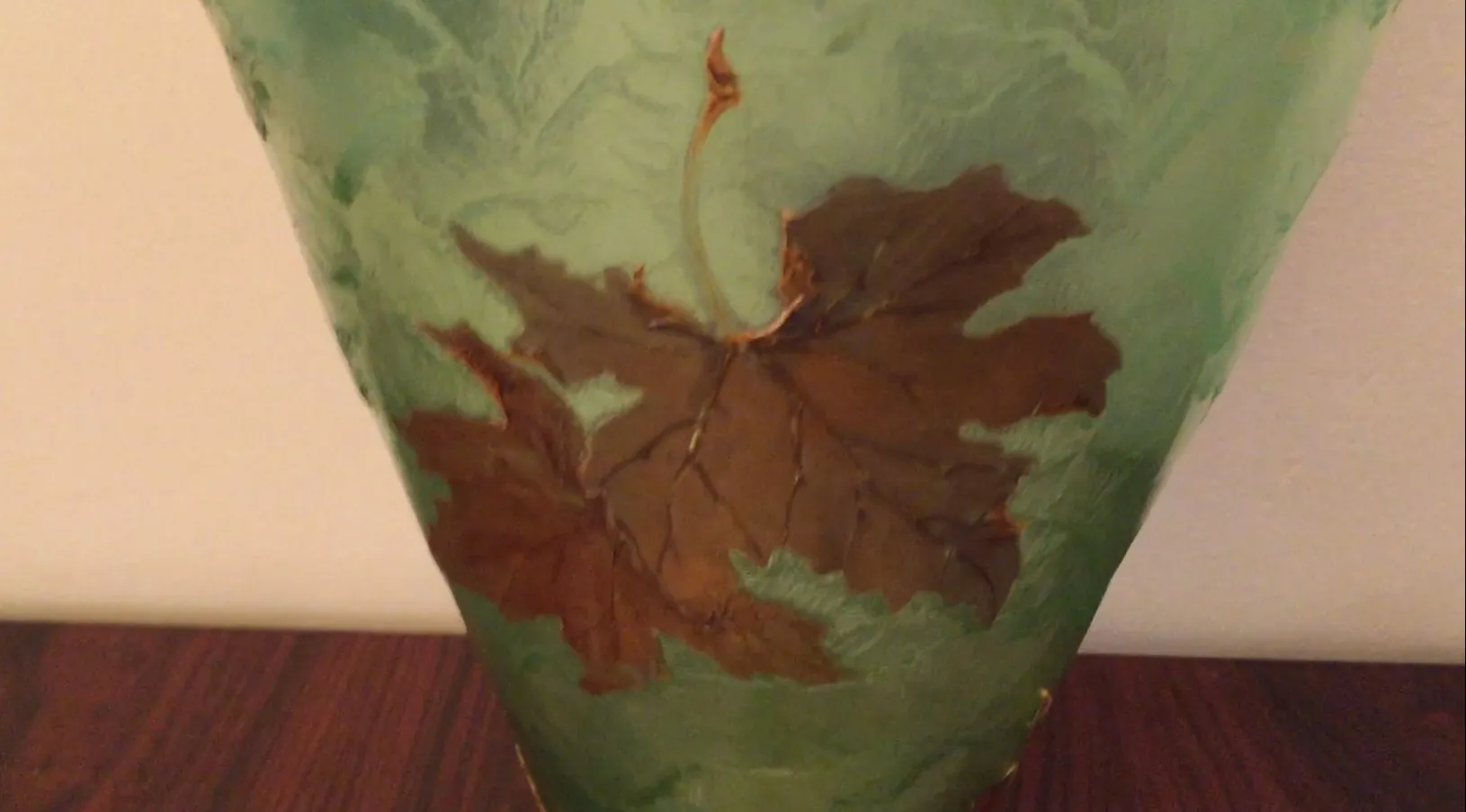 Glass globe with brown and green leaf decoration.