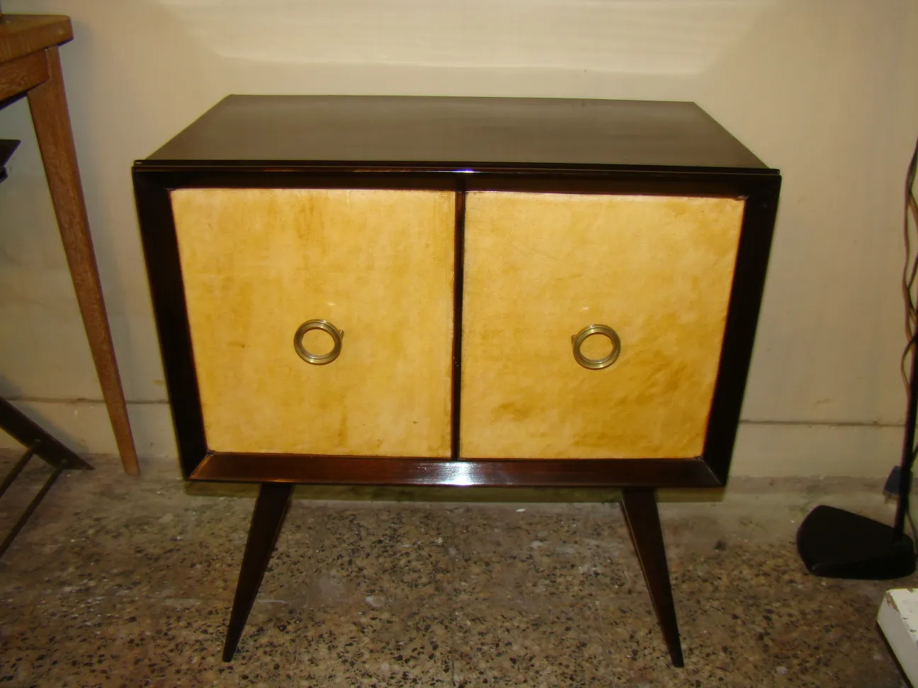 Antique bedside table with doors and elegant details in a neutral setting.